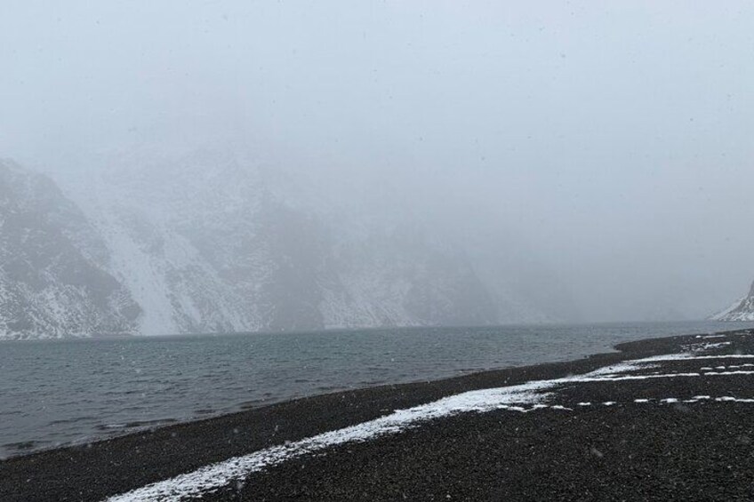 A foggy coastal landscape with a rocky shoreline and a mountain in the background. 3