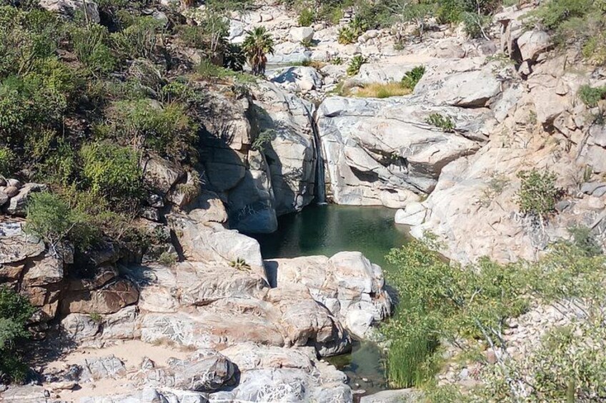 Un paysage rocheux avec un petit plan d’eau et une végétation clairsemée. 1
