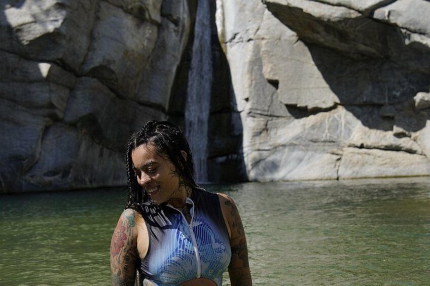 Une personne vêtue d’un maillot de bain bleu, debout dans l’eau, avec un paysage rocheux en arrière-plan. 5