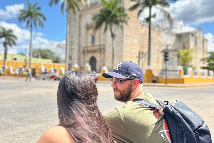A couple sitting in front of a historic building with palm trees and a clear sky. 5