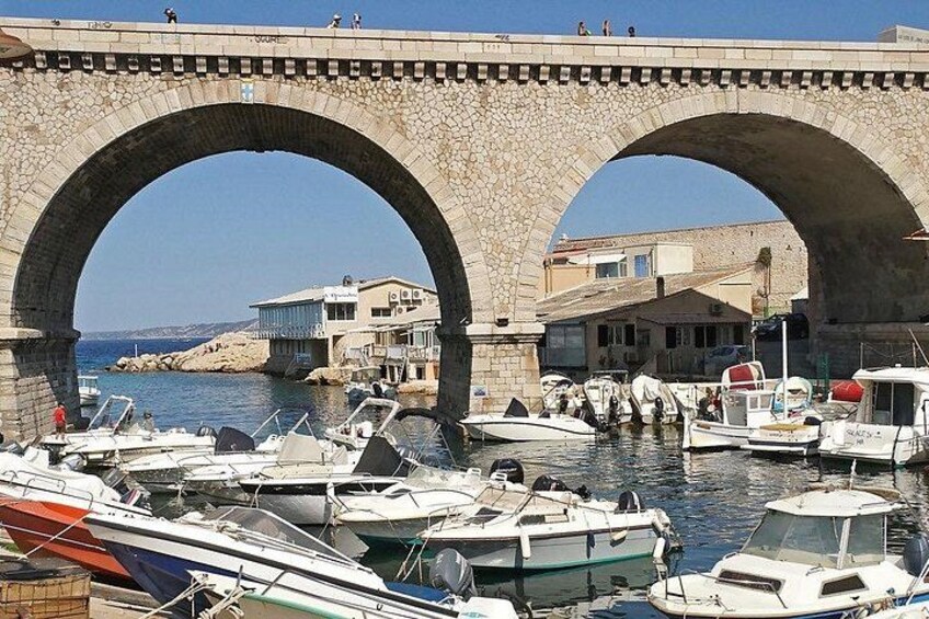 Eine Steinbrücke über einem Jachthafen mit vertäuten Booten. 5