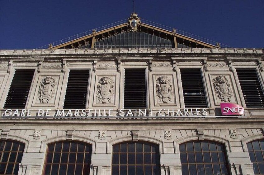 Eine historische Gebäudefassade mit aufwendigen architektonischen Details, darunter ein Wappen an der Spitze und mehrere Fenster mit Fensterläden. 2