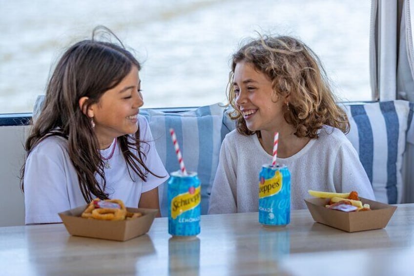 Two people sitting at a table with food and drinks. 5