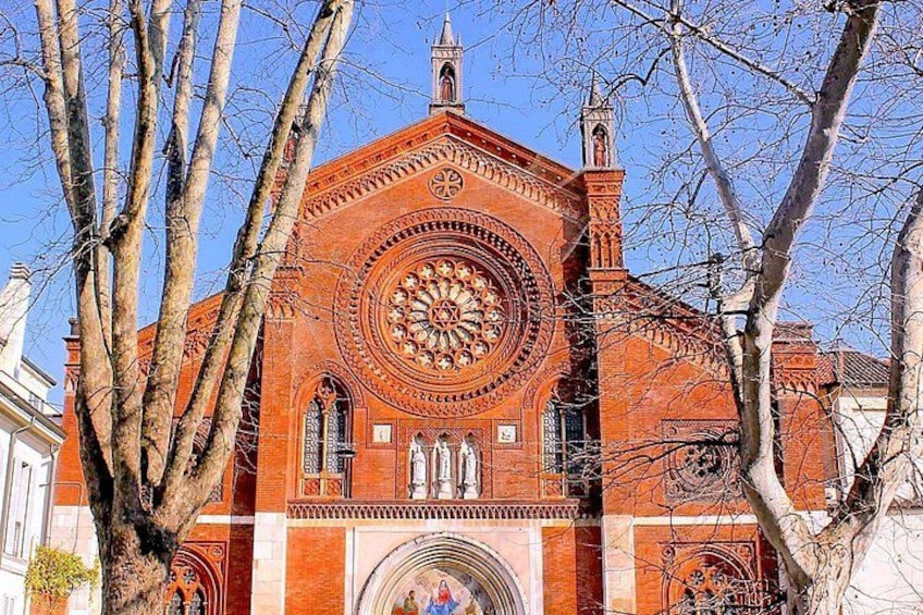 Una chiesa in mattoni rossi con un'ampia finestra circolare e un campanile. 1