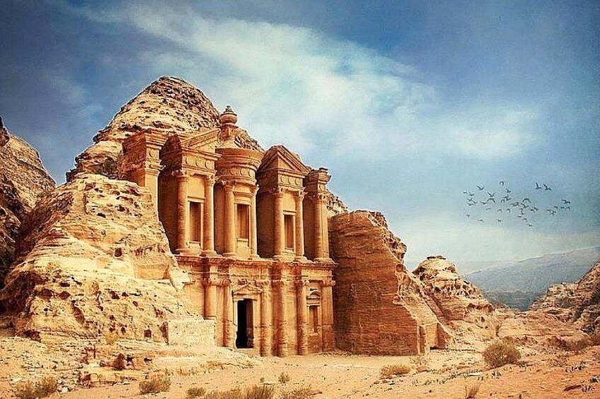 Una estructura de arenisca con columnas y un acceso, rodeada de terreno rocoso y vegetación escasa. 5