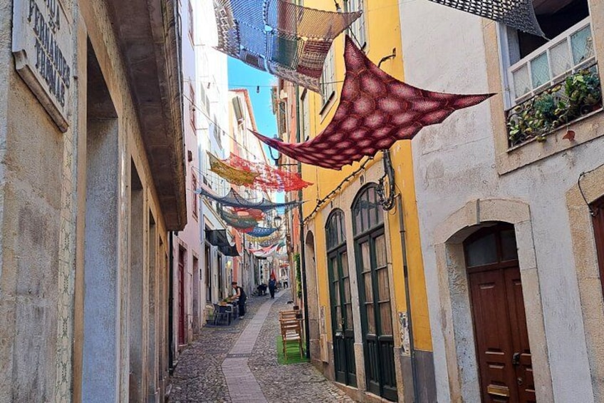 Una stretta via fiancheggiata da edifici colorati, un sentiero acciottolato e decorazioni pensili. 2