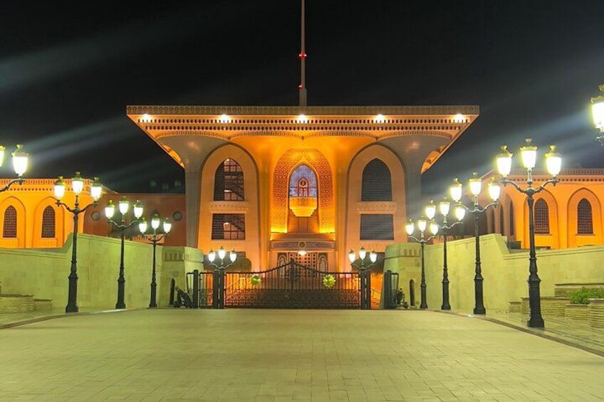 A well-lit building with arched windows and a central dome, surrounded by a paved area and street lamps. 5