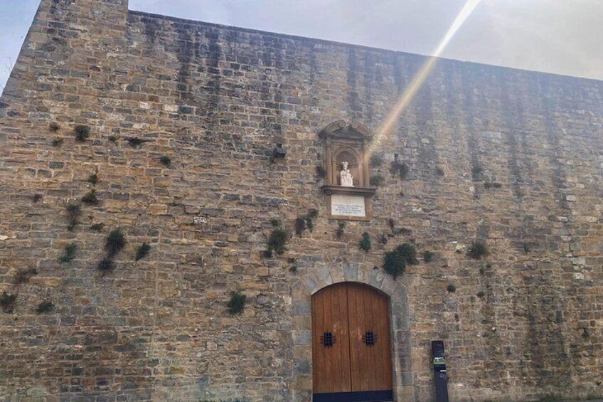A stone wall with a wooden door and a statue. 1