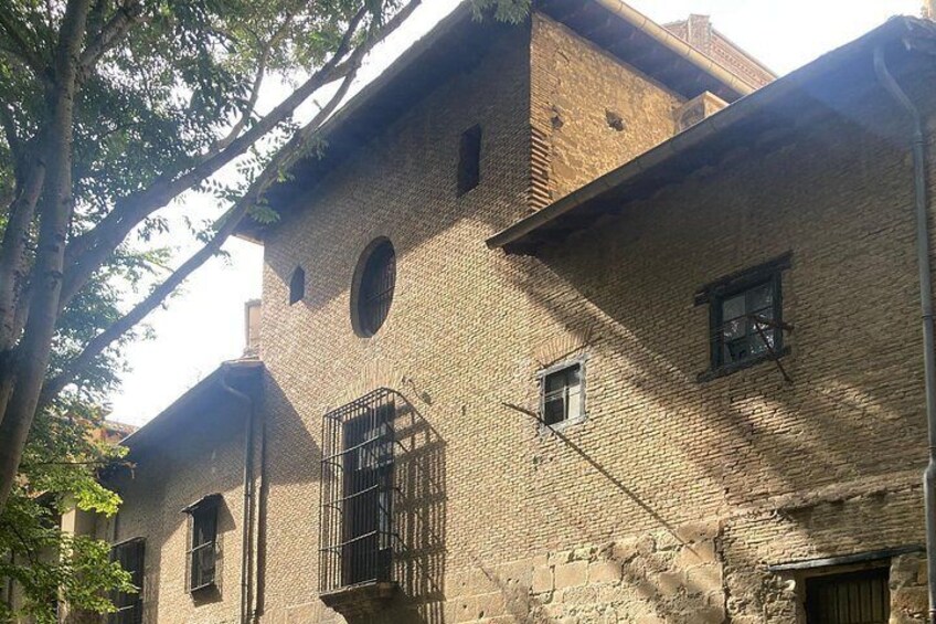 A historic brick building with arched windows and a barred window. 3