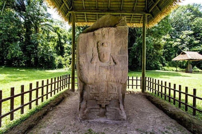 A stone sculpture in a covered area with a wooden fence around it. 4