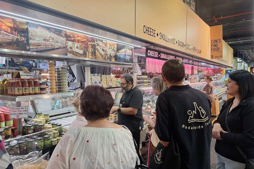 A grocery store with shelves stocked with cheese, small groceries, and other items. 4