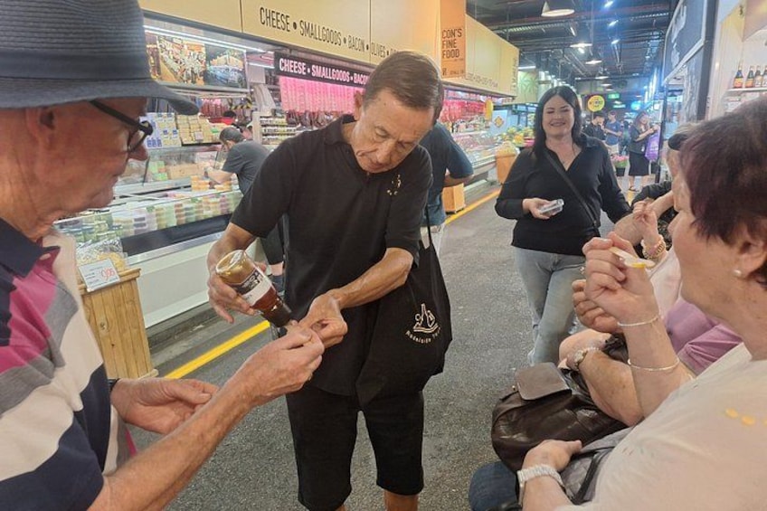 A person pouring a drink into a cup, surrounded by other people. 1