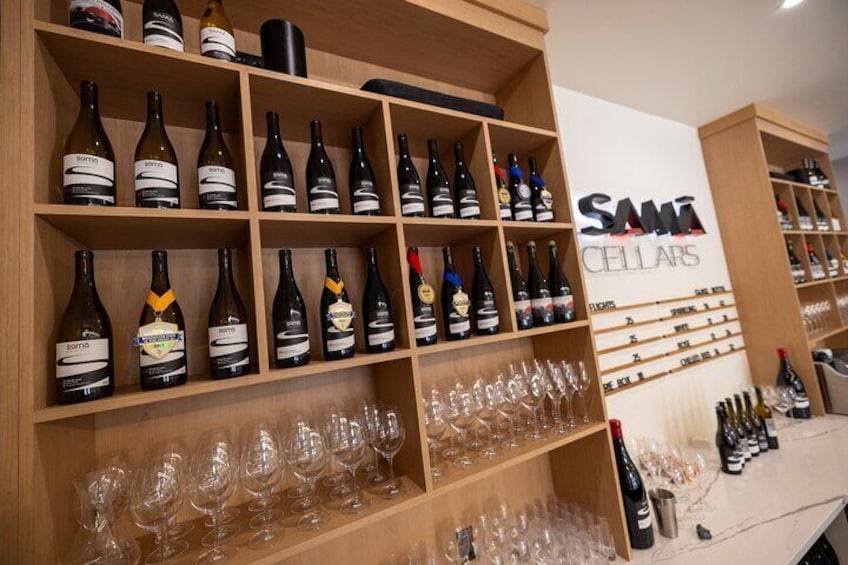 A wine cellar with shelves of wine bottles and glasses. 1