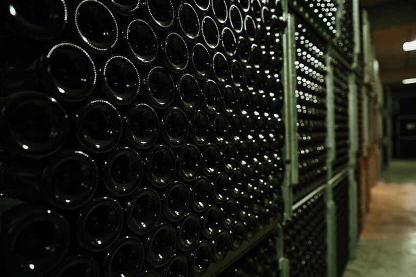 Un'area di stoccaggio con file di bottiglie di vino impilate. 3