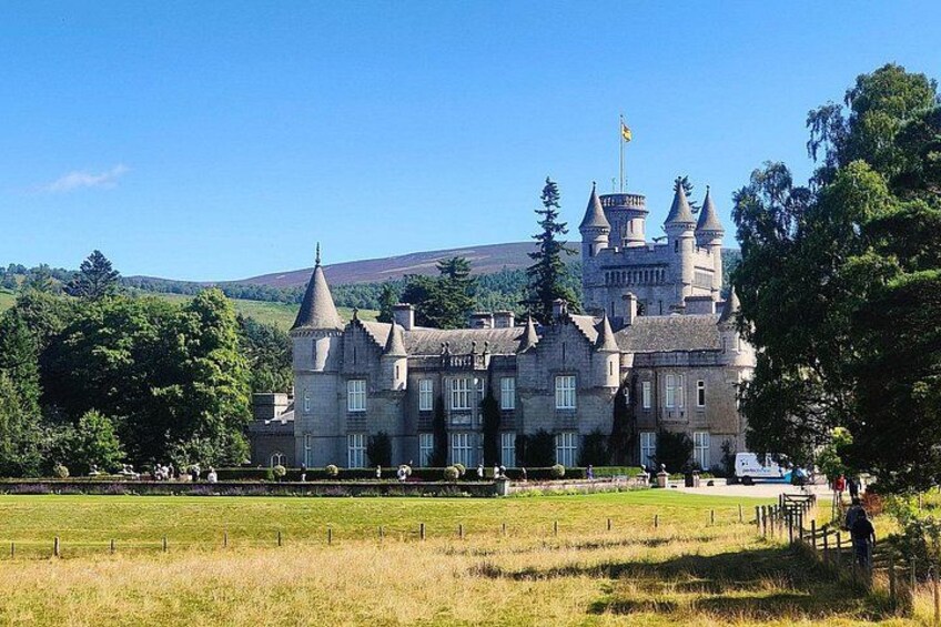 A large castle with multiple towers, surrounded by a grassy field and trees. 1