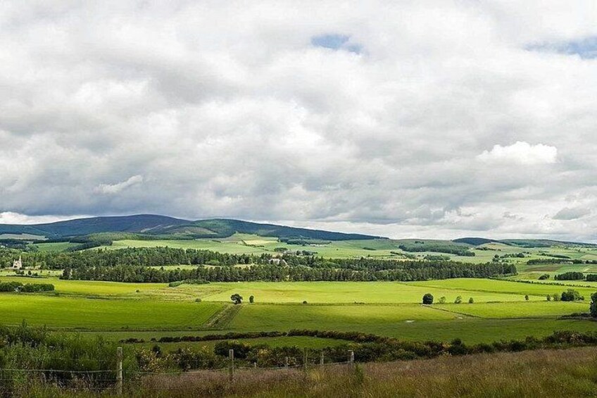 Rolling green hills, a church, and a cloudy sky. 4