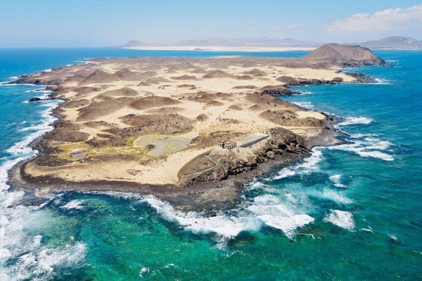 A coastal landscape with a sandy beach, rocky terrain, and clear blue waters. 2