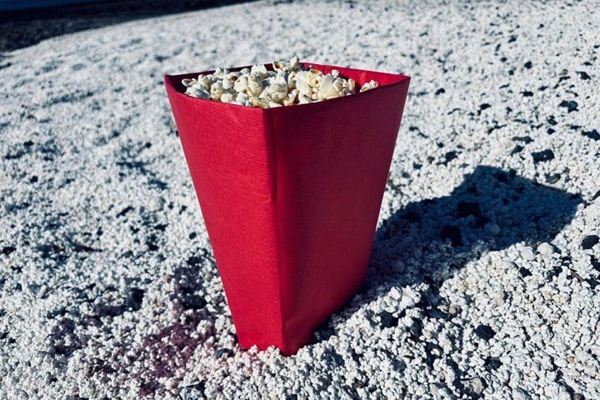A red popcorn container on a gravel surface. 3