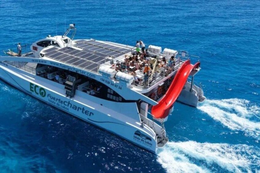A white boat with a red slide, solar panels, and the ECO logo. 3
