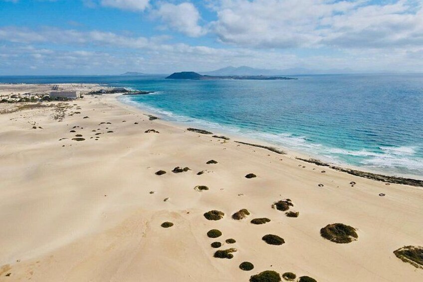 A sandy beach with footprints and a calm sea. 2