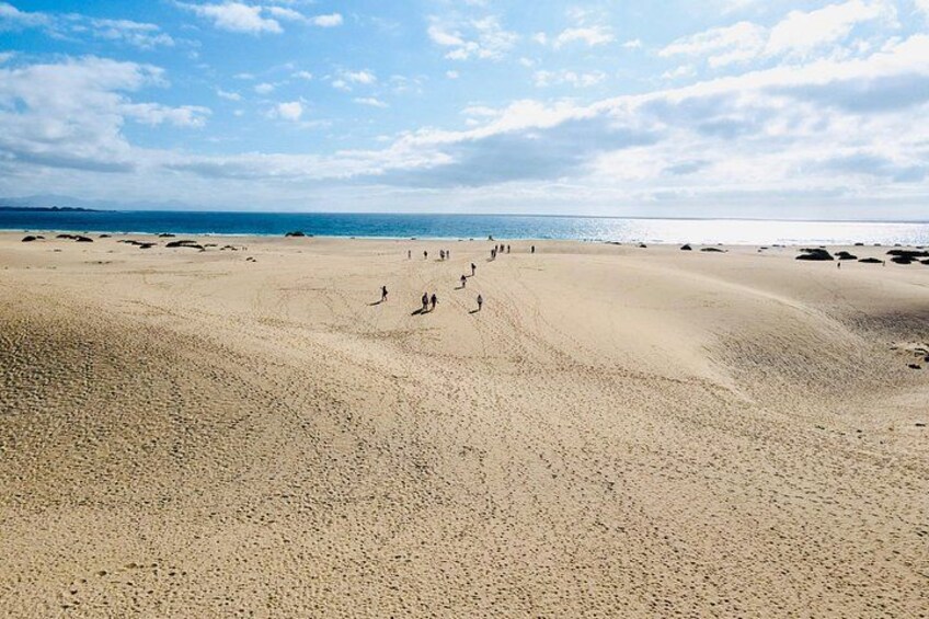A sandy beach with people walking and a clear sky. 3