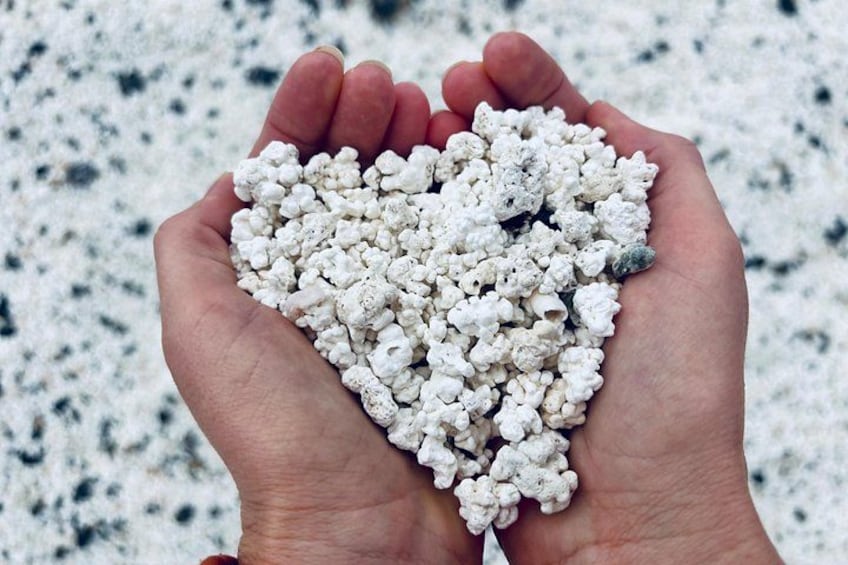 A hand holding a heart-shaped pile of white pebbles. 2