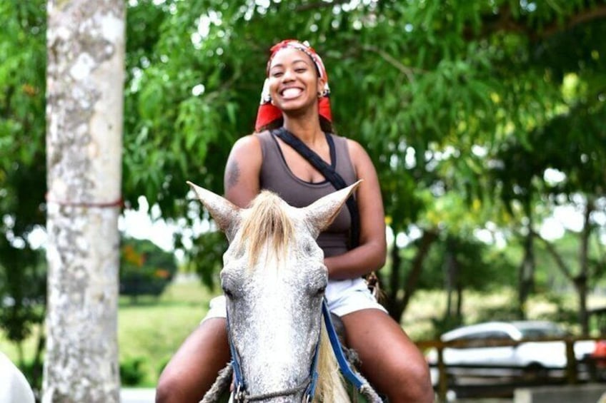 A person riding a horse in a park with trees and a fence in the background. 5