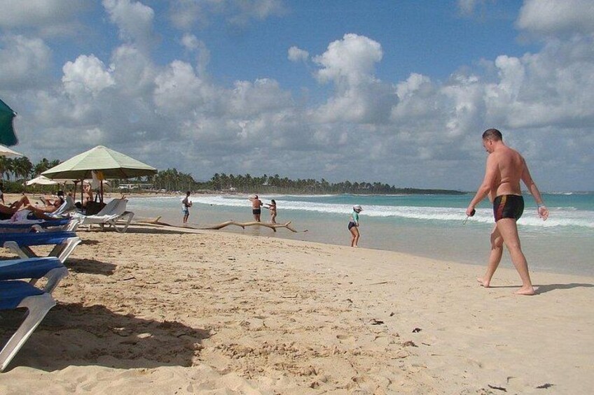 A beach with people sunbathing, walking, and swimming. 5