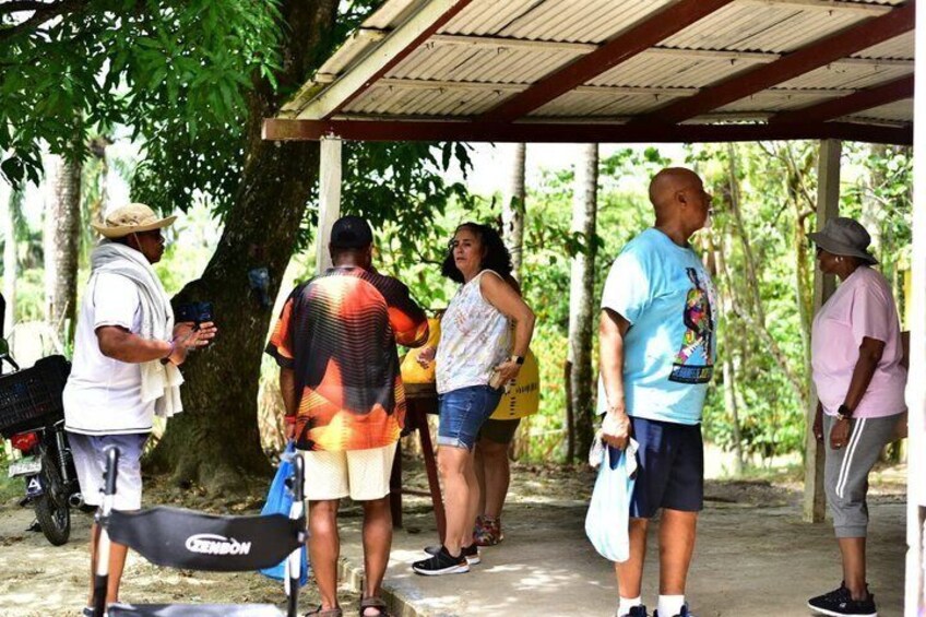 People standing under a covered area with trees in the background. 2
