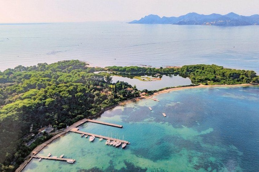 An aerial view of a coastal area with clear turquoise waters, a dock, and a small island with dense greenery. 2