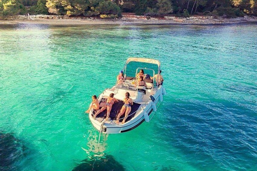 Un bote con gente en un mar turquesa, rodeado de aguas cristalinas y una costa rocosa con árboles. 2