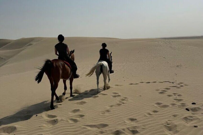 Tre personer rider på heste i en ørken med sandklitter. 2