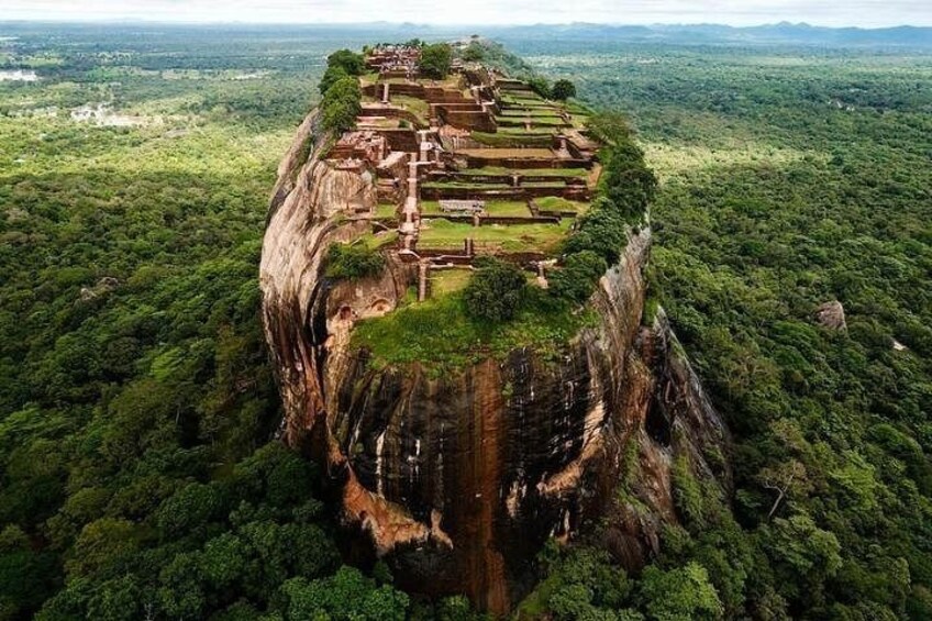 An ancient cliffside temple complex surrounded by dense forest. 4