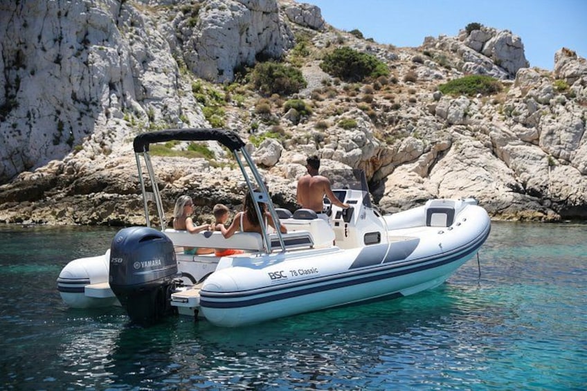 A small inflatable boat with a Yamaha outboard motor, docked near rocky cliffs. 2