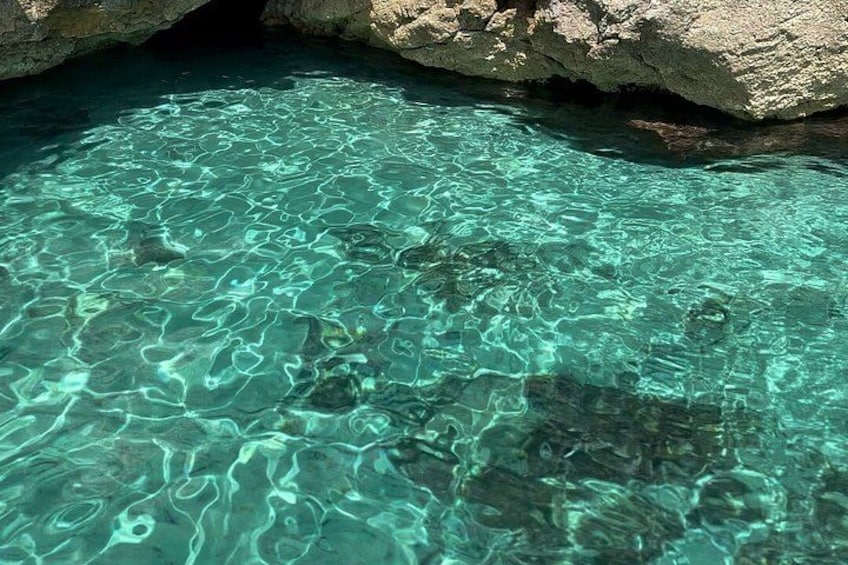 Clear turquoise water, rocky formations, and a cave entrance. 5