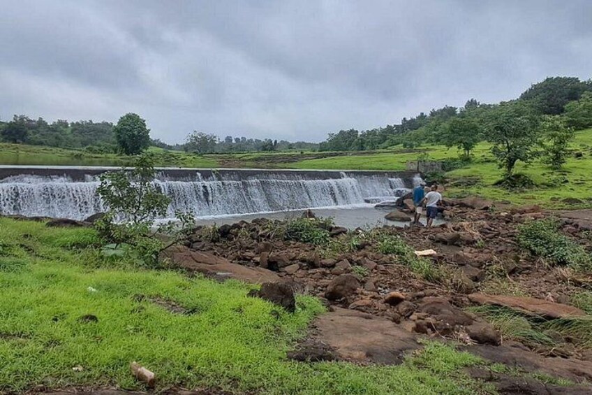A waterfall, rocky terrain, and a person standing near the water. 2