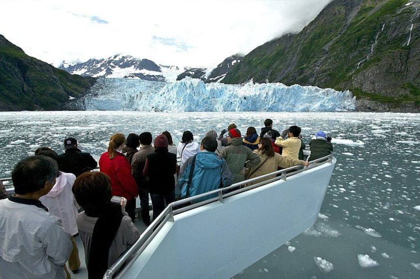 A group of people on a boat observing a glacier. 2