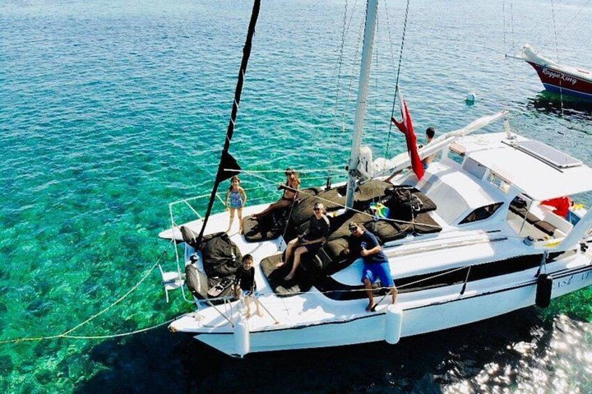 Un velero con gente a bordo, anclado en aguas azules y cristalinas. 3