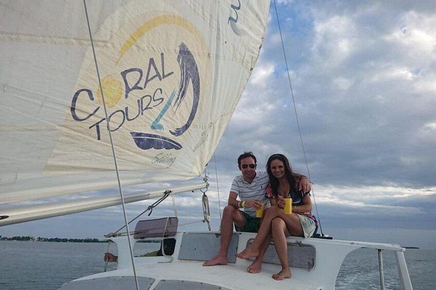 Un velero con un logotipo que dice 'CORAL TOURS' y dos personas sentadas en la cubierta. 2