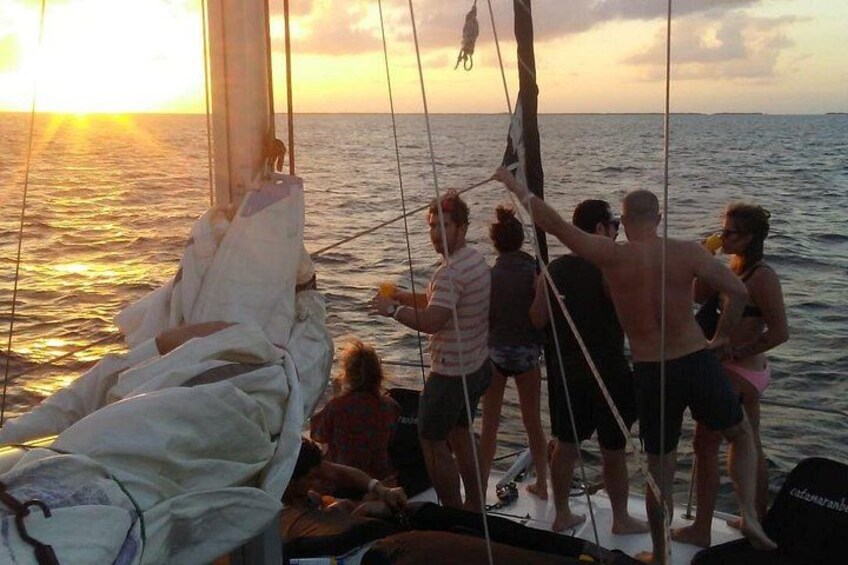 Un grupo de personas navegando en un velero al atardecer. 5