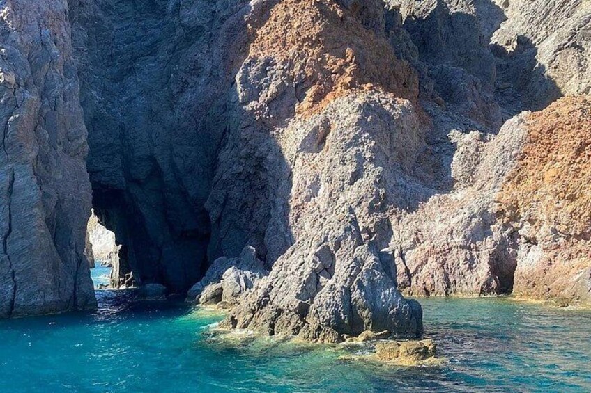 A coastal rock formation with a natural archway and clear turquoise waters. 2