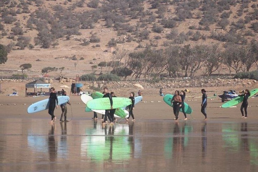 Een groep mensen loopt over het strand met surfplanken. 4