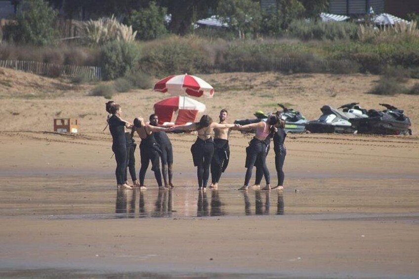 Een groep mensen op het strand, met een rode en witte parasol op de achtergrond. 5