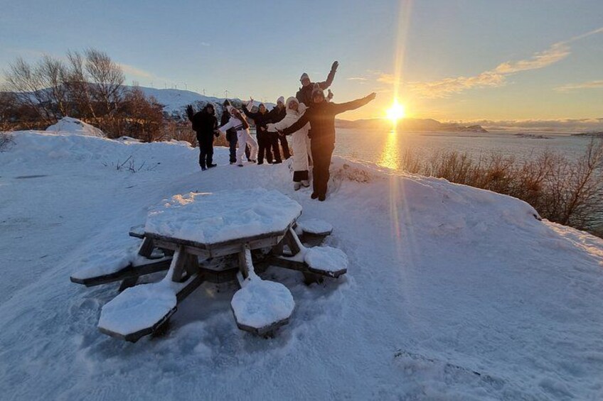 A group of people standing on a snowy landscape with a sunset in the background. 5
