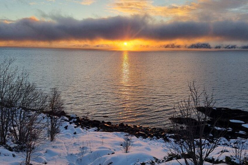 A sunset over a calm lake with snow on the shore. 2