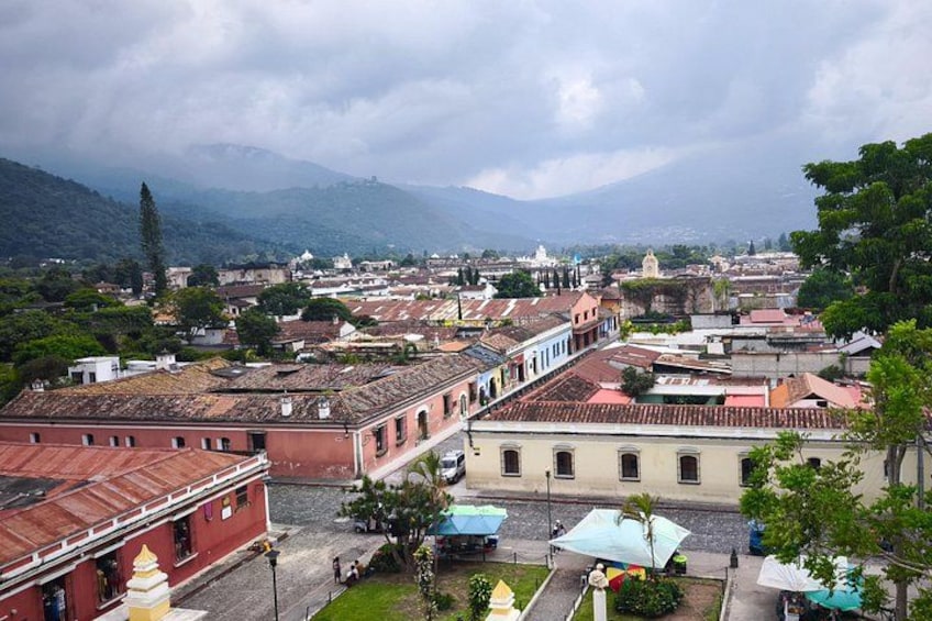A cityscape with historic buildings, a prominent church, and a mountainous backdrop. 3