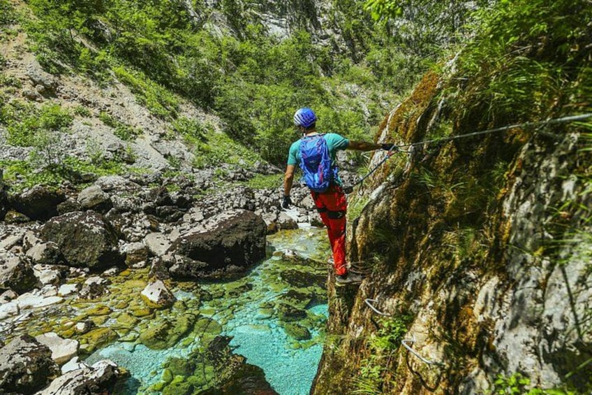 A person crossing a rocky stream in a forested area. 1