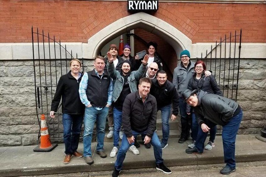 A group of people standing in front of a building with a sign that reads "RYMAN". 3