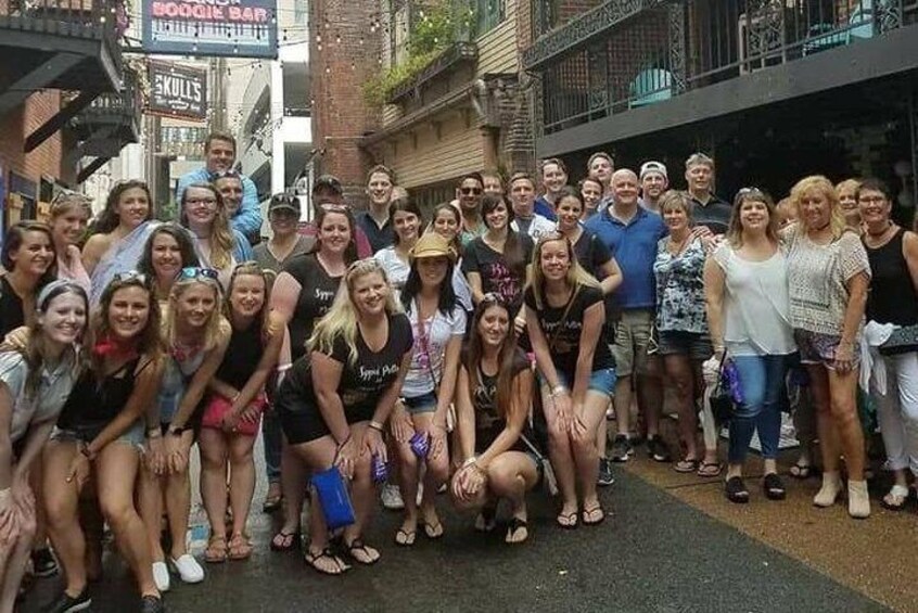 A group of people posing for a photo on a street with buildings and signs in the background. 4