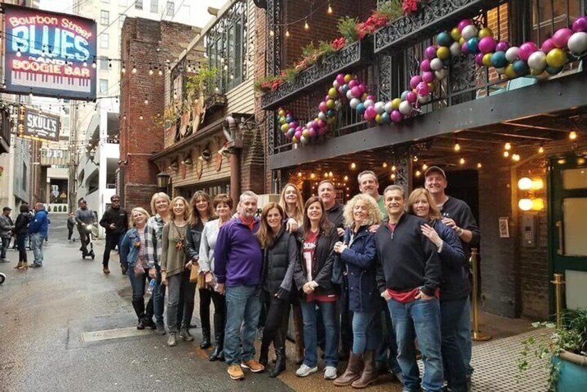 A group of people standing in front of a building with a sign that reads "Bourbon Street Blues". 1